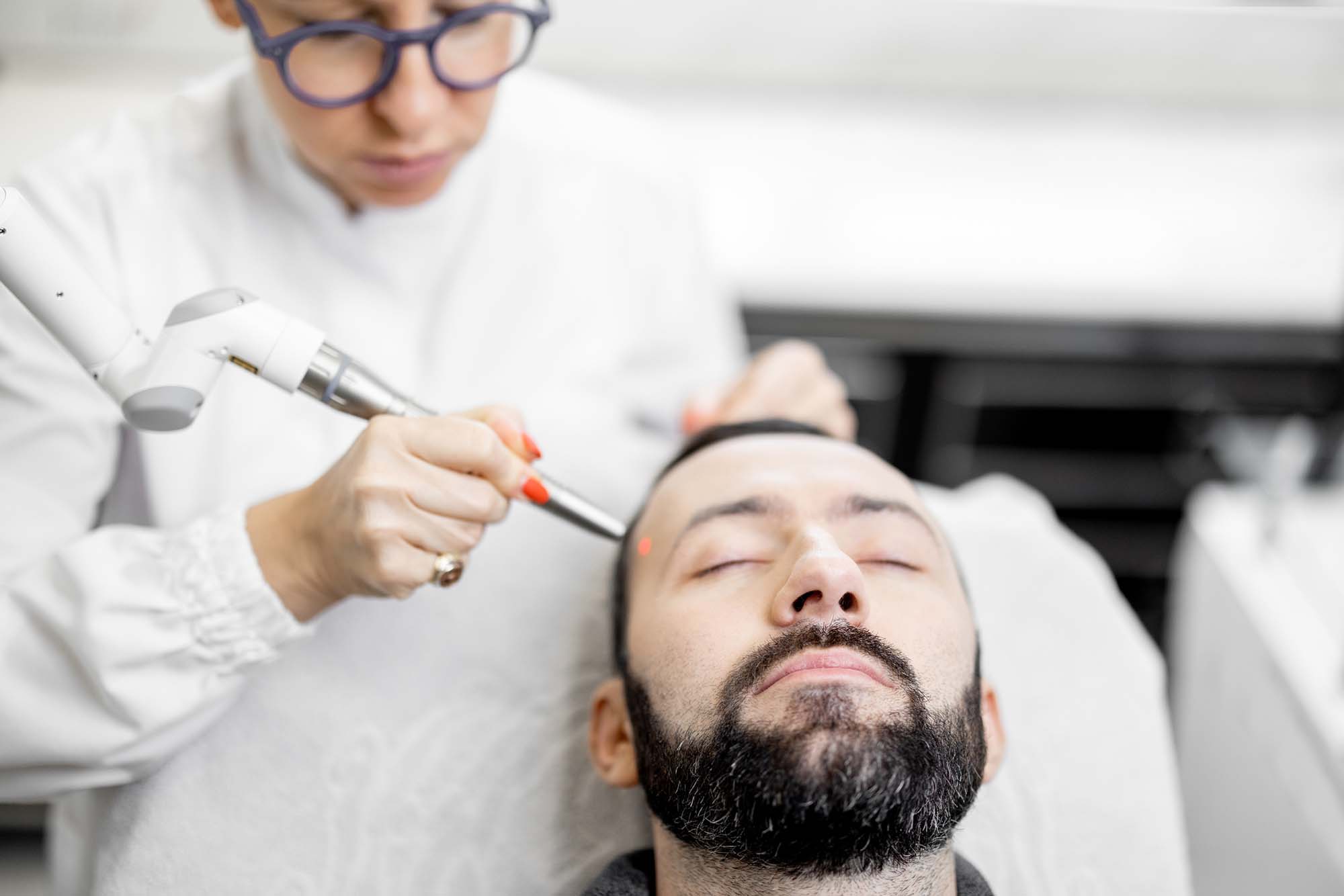 Cosmetologist doing laser facelifting procedure in beauty clinic Cosmetologist doing laser facelifting procedure in beauty clinic