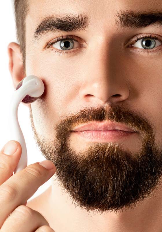 Handsome man using meso roller for better beard growth